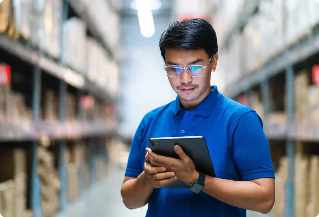 man in warehouse wearing blue shirt holding a tablet